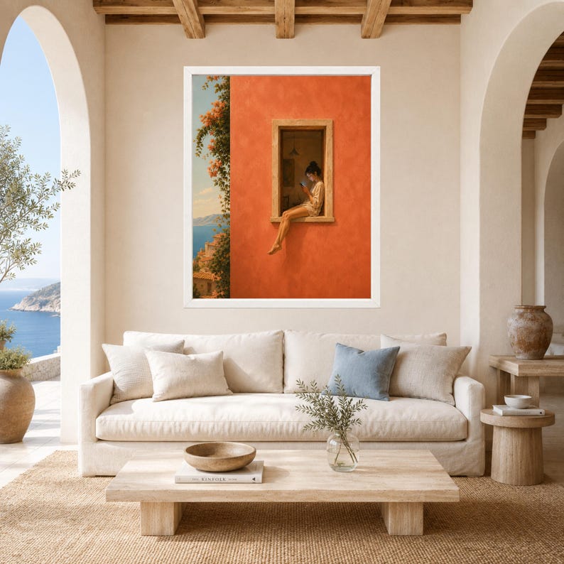 K&ouml;nnte beinhalten: Ein gerahmter Wandkunstdruck, der eine Person zeigt, die auf dem Fensterbrett eines leuchtend orangefarbenen Geb&auml;udes sitzt und ein Buch liest. Die Szene umfasst einen Blick auf das blaue Meer und K&uuml;stenklippen mit orangefarbenen Blumen.