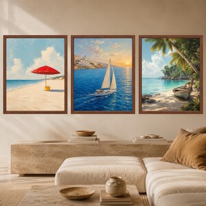 May include: A set of three square wall art prints in brown frames. The left print shows a red beach umbrella on sand. The center print depicts a sailboat on blue water near a coastal town. The right print features a boat on a tropical beach.