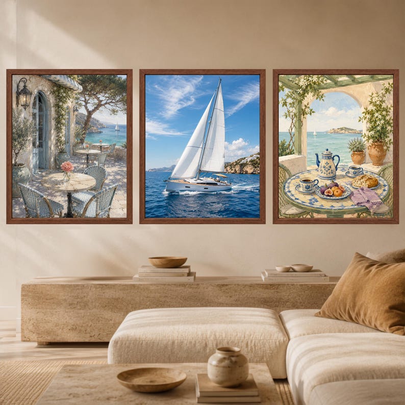 Puede incluir: Un conjunto de tres cuadros enmarcados con escenas costeras. La imagen de la izquierda muestra un patio con sillas y una mesa frente al mar. La imagen central representa un velero blanco en el agua. La imagen de la derecha muestra una mesa.