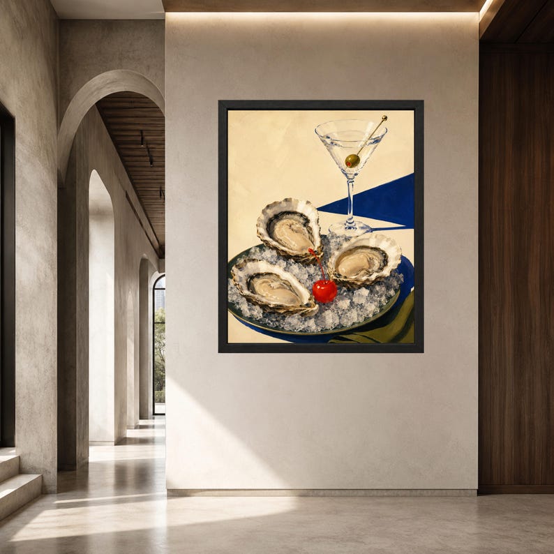 May include: A framed wall art print featuring three raw oysters served on a bed of crushed ice on a plate, accompanied by a martini glass with a single green olive and a bright red cherry placed next to the oysters on a blue and yellow surface.