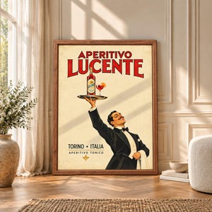 Framed vintage Italian aperitivo wall art showing a smiling tuxedoed waiter raising a tray with a bottle and red cocktail beneath bold Aperitivo Lucente and Torino Italia typography.