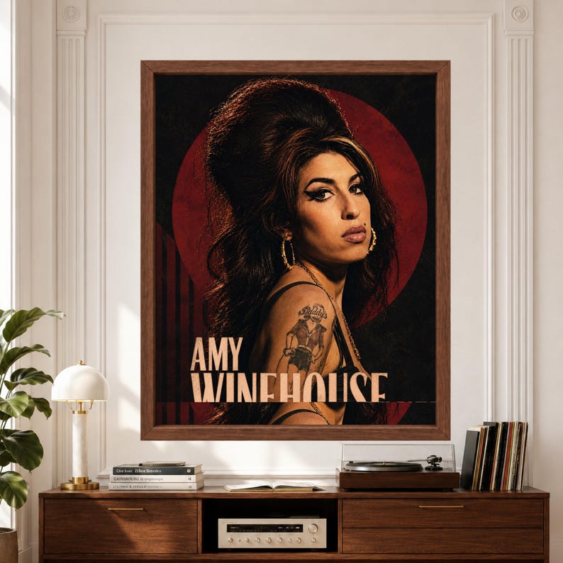 Framed Amy Winehouse wall art featuring a vintage-inspired retro soul portrait with signature beehive hair, winged eyeliner and tattoos against a burgundy circle and black background with bold Amy Winehouse typography above a record player console.