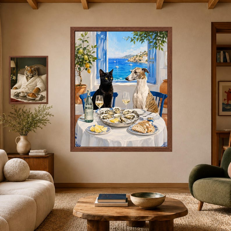 Puede incluir: Una gran l&aacute;mina de arte enmarcada que muestra a un gato negro y un perro atigrado sentados a una mesa redonda con ostras, pan y vino, frente a un mar azul. Una l&aacute;mina m&aacute;s peque&ntilde;a muestra a un tigre en albornoz durante el desayuno.