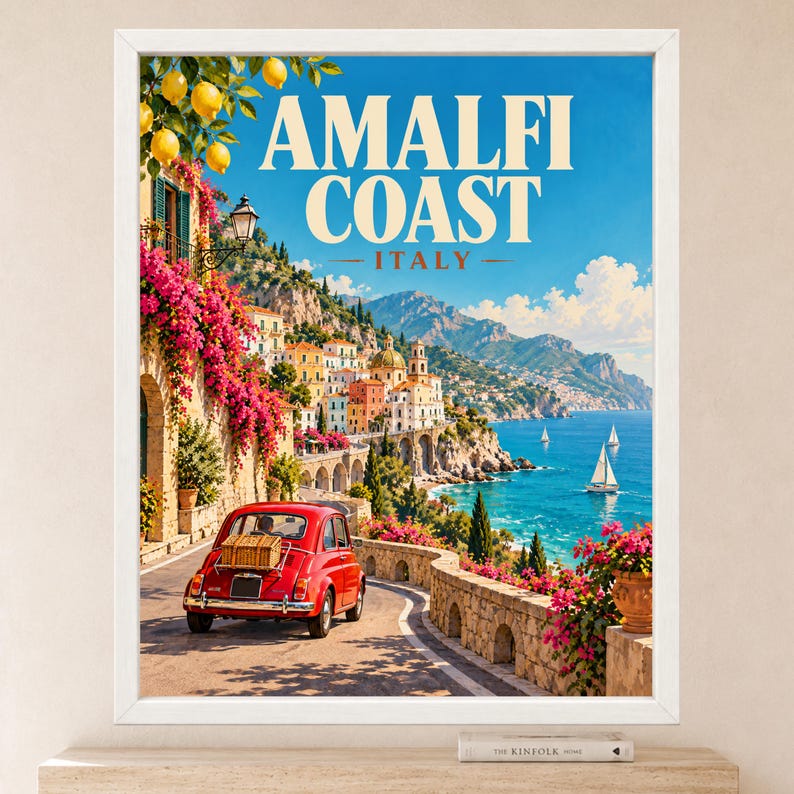 May include: A framed travel poster featuring the Amalfi Coast in Italy. The scene shows a red vintage car on a coastal road, vibrant pink bougainvillea, yellow lemons, and sailboats on the blue sea. The text reads AMALFI COAST ITALY.