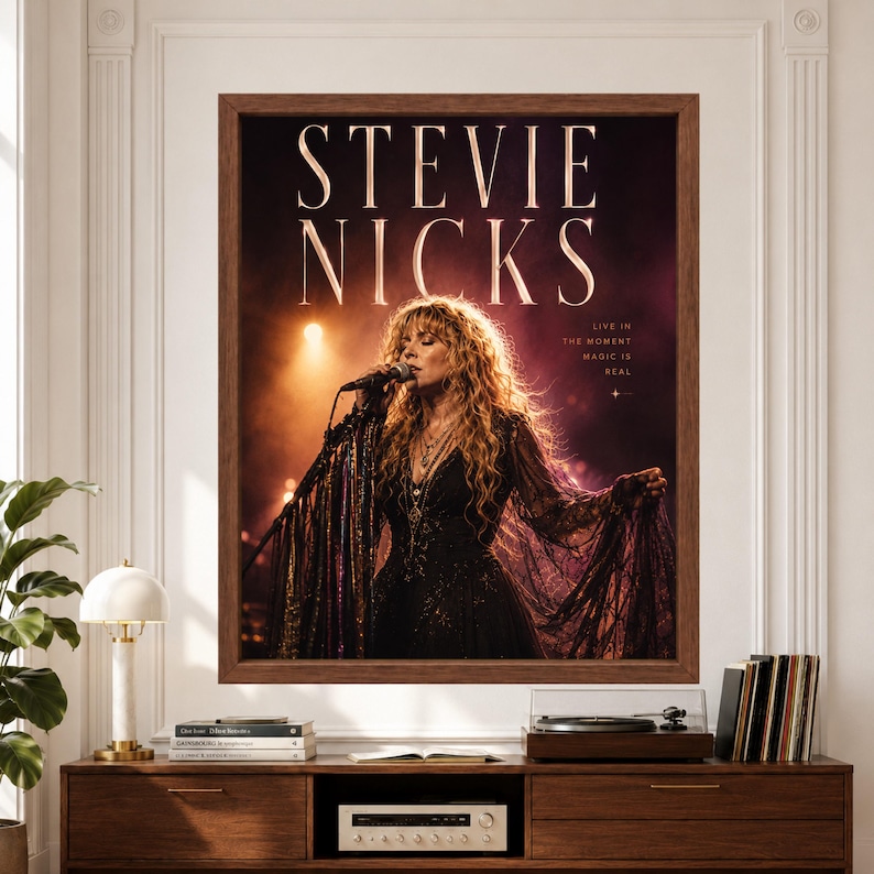 Framed music poster labeled Stevie Nicks showing a female rock singer performing at a microphone in a flowing black lace dress under warm amber and purple concert lights.