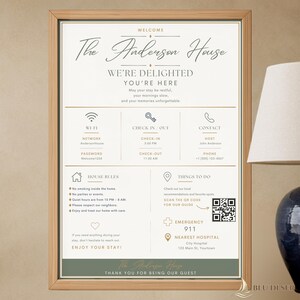 Op de afbeelding: Een ingelijst welkomstbord voor The Anderson House met een witte achtergrond, donkere tekst en gouden accenten. Het bevat secties voor wifi, in- en uitchecktijden, contactgegevens, huisregels, een QR-code en informatie voor noodgevallen.