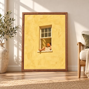 Framed yellow wall art showing a barefoot woman sitting in a small open window reading an orange book against a large textured sunlit yellow facade.