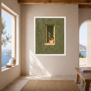 May include: A framed wall art print featuring a textured olive green wall with a central rectangular window. A person sits inside the window frame, reading an orange book while wearing a light-colored dress, illuminated by sunlight.