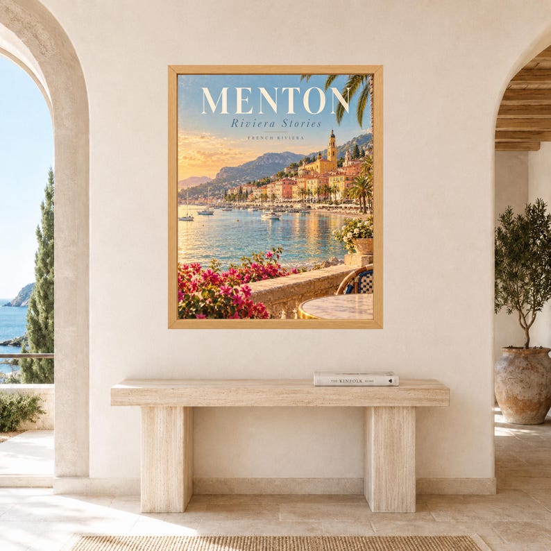May include: A framed wall art print featuring a scenic view of the Menton coastline on the French Riviera. The image displays a coastal town with colorful buildings, a blue sea, boats, and pink flowers in the foreground. The text reads MENTON.