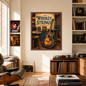 Op de afbeelding: Een ingelijste muurkunstprint getiteld Whiskey Strings met een akoestische gitaar die tegen een houten kruk in een bar leunt, met een glas whisky op een tafel, naast twee kleinere ingelijste prints met een muziekthema aan de muur.