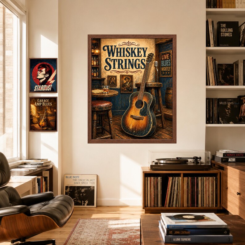 Op de afbeelding: Een ingelijste muurkunstprint getiteld Whiskey Strings met een akoestische gitaar die tegen een houten kruk in een bar leunt, met een glas whisky op een tafel, naast twee kleinere ingelijste prints met een muziekthema aan de muur.