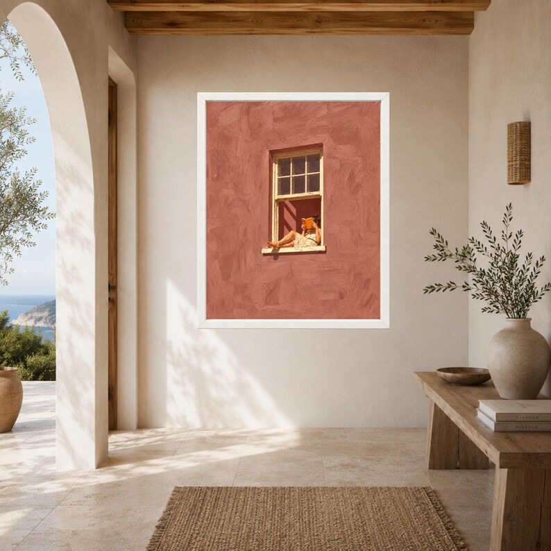 May include: A framed wall art print featuring a terracotta-colored textured wall with a single window. A person is seated in the window frame, reading an orange book. The artwork is enclosed in a simple white frame, displaying a scene of leisure.