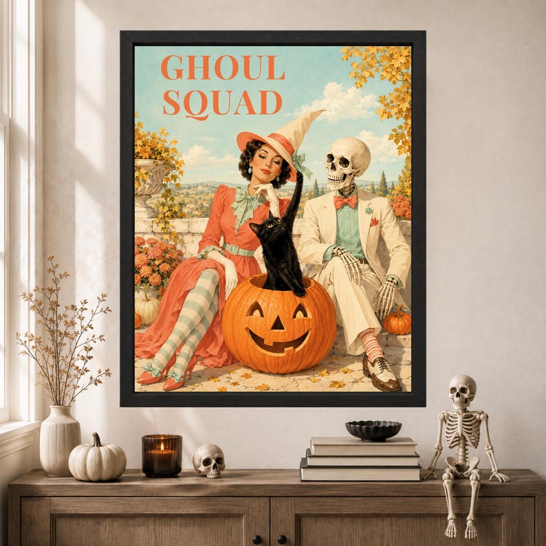 May include: A framed wall art print titled GHOUL SQUAD featuring a vintage-style illustration of a person in a witch hat and a skeleton sitting together with a black cat inside a carved orange pumpkin against a backdrop of autumn trees.