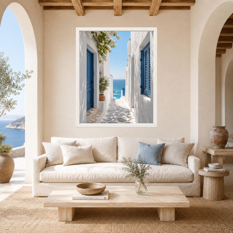 K&ouml;nnte beinhalten: Ein gerahmter Wandkunstdruck, der eine schmale wei&szlig;e Gasse mit leuchtend blauen T&uuml;ren und Fensterl&auml;den zeigt, die den Blick auf das blaue Meer unter klarem Himmel freigibt. Die Szene umfasst Steinwege, gr&uuml;nes Blattwerk und wei&szlig;e Architektur.