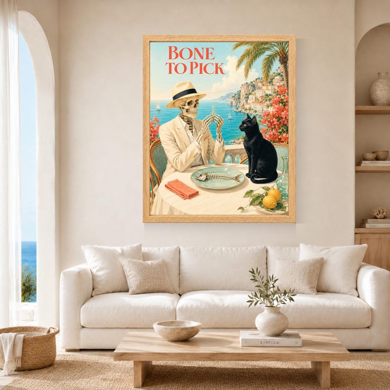 Peut inclure: Une impression d'art encadr&eacute;e intitul&eacute;e BONE TO PICK repr&eacute;sentant un squelette en costume et chapeau beiges assis &agrave; une table avec un chat noir. La sc&egrave;ne montre un paysage c&ocirc;tier avec une ar&ecirc;te de poisson, une serviette rouge et deux citrons.