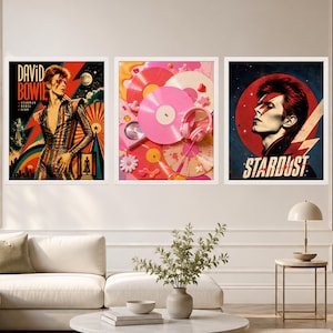 May include: Three framed wall art prints featuring David Bowie imagery. The left print shows Bowie in a striped suit with the text "DAVID BOWIE STARMAN REBEL ICON". The centre print displays pink vinyl records and headphones. The right print shows Bowie with a lightning bolt and the text "STARDUST".