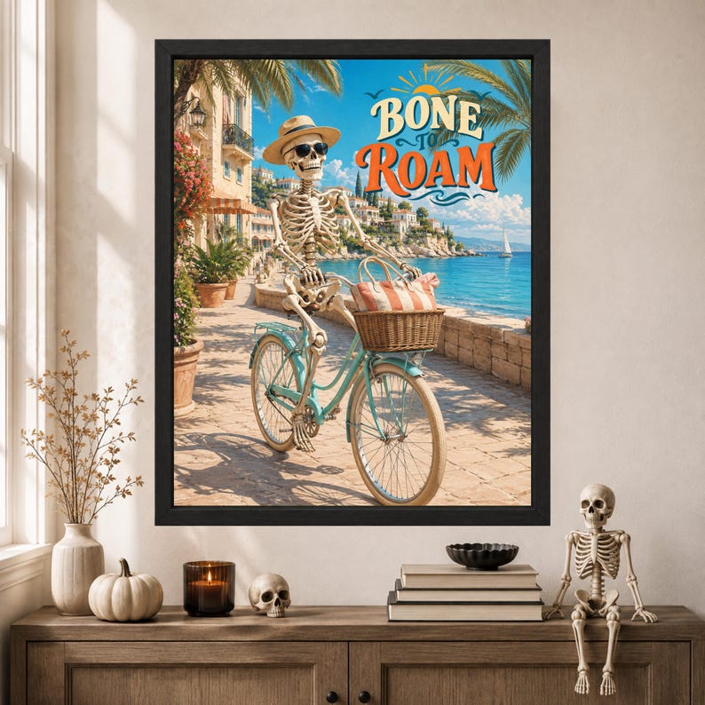 Peut inclure: Une impression d'art encadr&eacute;e repr&eacute;sentant un squelette portant un chapeau de paille et des lunettes de soleil, sur un v&eacute;lo bleu clair avec un panier en osier contenant un sac ray&eacute;. Le texte BONE TO ROAM surplombe une sc&egrave;ne c&ocirc;ti&egrave;re avec des palmiers.