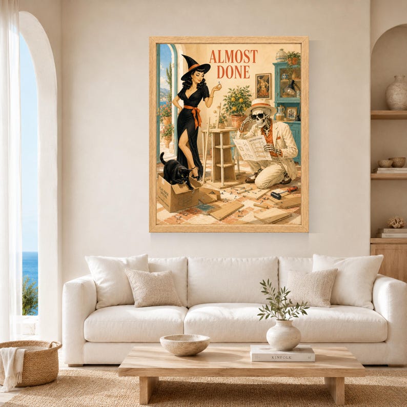 May include: A framed wall art print featuring a retro-style illustration of a woman in a black dress and witch hat standing next to a skeleton in a beige suit reading instructions. A black cat sits in a cardboard box. The text ALMOST DONE is at the top.