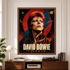 Framed David Bowie wall art featuring a vintage-inspired Starman portrait with red hair, bold red and blue lightning graphics, celestial stars, cosmic symbols and large David Bowie typography above a record player console.