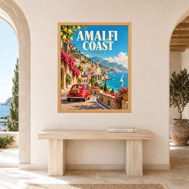 May include: A framed wall art print featuring a scenic view of the Amalfi Coast in Italy. The image displays a red vintage car on a coastal road, vibrant pink bougainvillea flowers, lemon branches, and sailboats on the blue sea. Text reads AMALFI COAST ITALY.