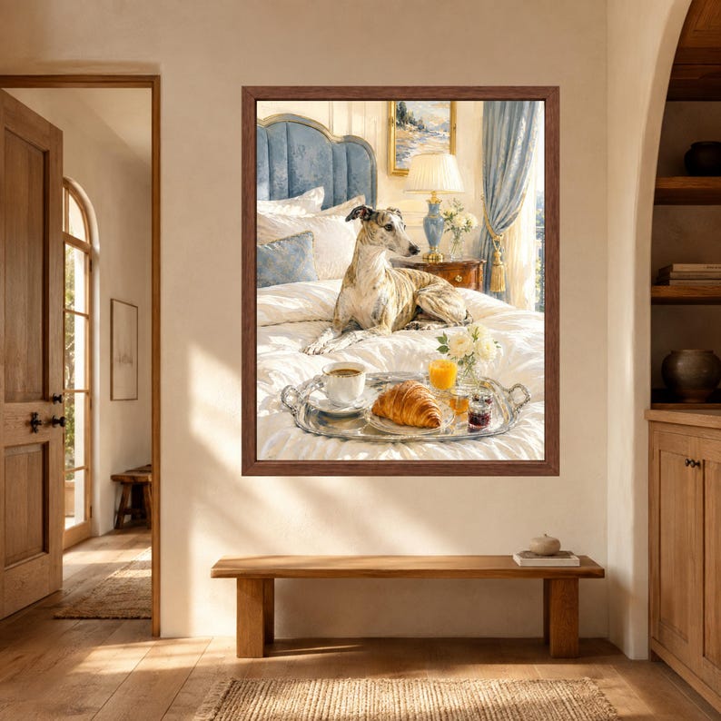 May include: A framed wall art print depicting a brindle greyhound resting on a white bed with a blue headboard. In the foreground, a silver tray holds a croissant, a cup of coffee, a glass of orange juice, and a small vase of white flowers.