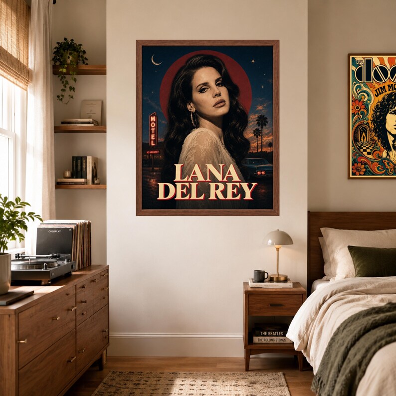 Puede incluir: Un p&oacute;ster de pared enmarcado que presenta un retrato de Lana Del Rey contra un cielo nocturno azul oscuro con una luna roja, palmeras, un letrero de motel y un coche antiguo. El texto LANA DEL REY est&aacute; impreso en letras may&uacute;sculas grandes y crema.