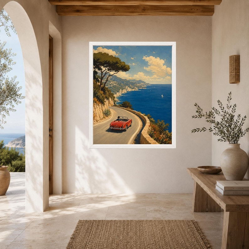 May include: A framed wall art print depicting a red convertible car driving along a winding coastal road. The scene features a deep blue sea, rocky cliffs, and a clear sky with scattered clouds, capturing a scenic Mediterranean landscape view.