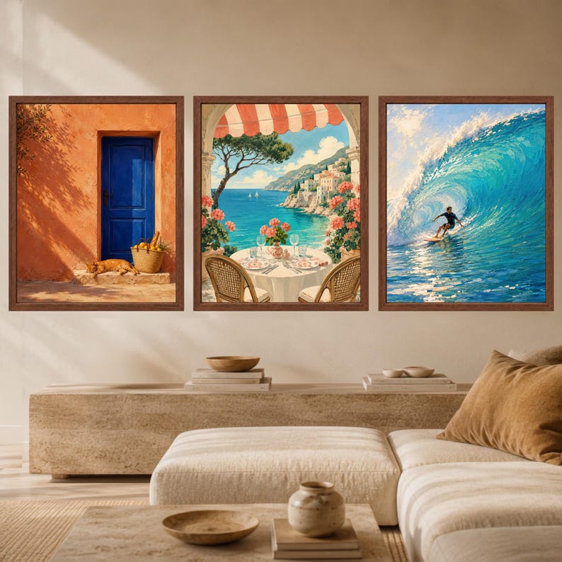 May include: A set of three framed wall art prints featuring a blue door with a cat, a coastal dining scene with a sea view, and a surfer riding a large blue ocean wave. Each print is enclosed in a dark brown wooden frame, displayed together.