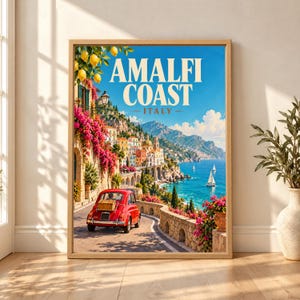 Framed Amalfi Coast Italy travel poster showing a red vintage car on a sunny coastal road with lemons, pink bougainvillea, cliffside houses, blue Mediterranean water and sailboats.
