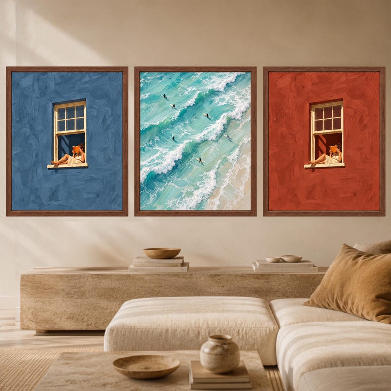 May include: A triptych of three framed wall art prints. The left print shows a person reading in a window against a blue wall. The center print depicts an aerial view of surfers in turquoise ocean waves. The right print shows a person reading in a window against a red wall.
