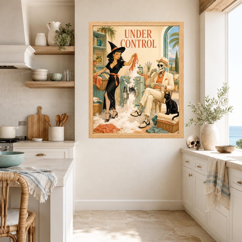 May include: A framed wall art print titled UNDER CONTROL featuring a vintage-style illustration of a witch in a black dress doing laundry with a skeleton in a beige suit and hat sitting nearby, accompanied by a black cat in a bright room.