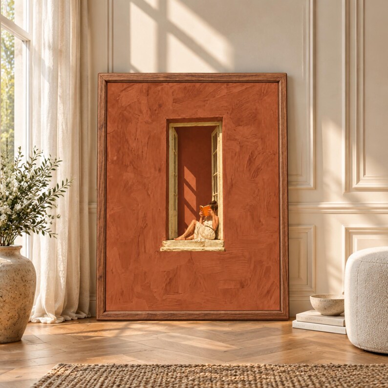 Framed terracotta wall art showing a barefoot woman reading an orange book in a tall narrow open window surrounded by a textured rust-colored Mediterranean facade.