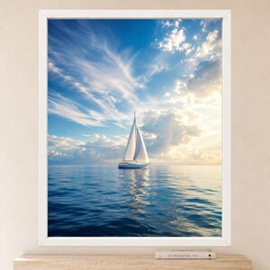 Pode incluir: Uma impress&atilde;o de arte de parede emoldurada apresentando um veleiro branco em &aacute;guas azuis calmas sob um c&eacute;u brilhante com nuvens finas e luz solar dourada. O veleiro est&aacute; centralizado, refletindo na &aacute;gua, dentro de uma moldura branca.