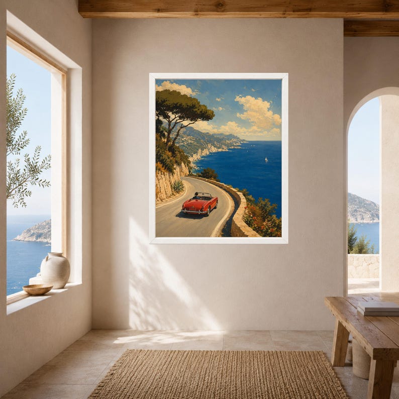 May include: A framed wall art print depicting a red convertible sports car driving along a winding coastal road. The scene features a deep blue sea, rocky cliffs, green trees, and a bright sky with scattered clouds, captured in a painterly style.