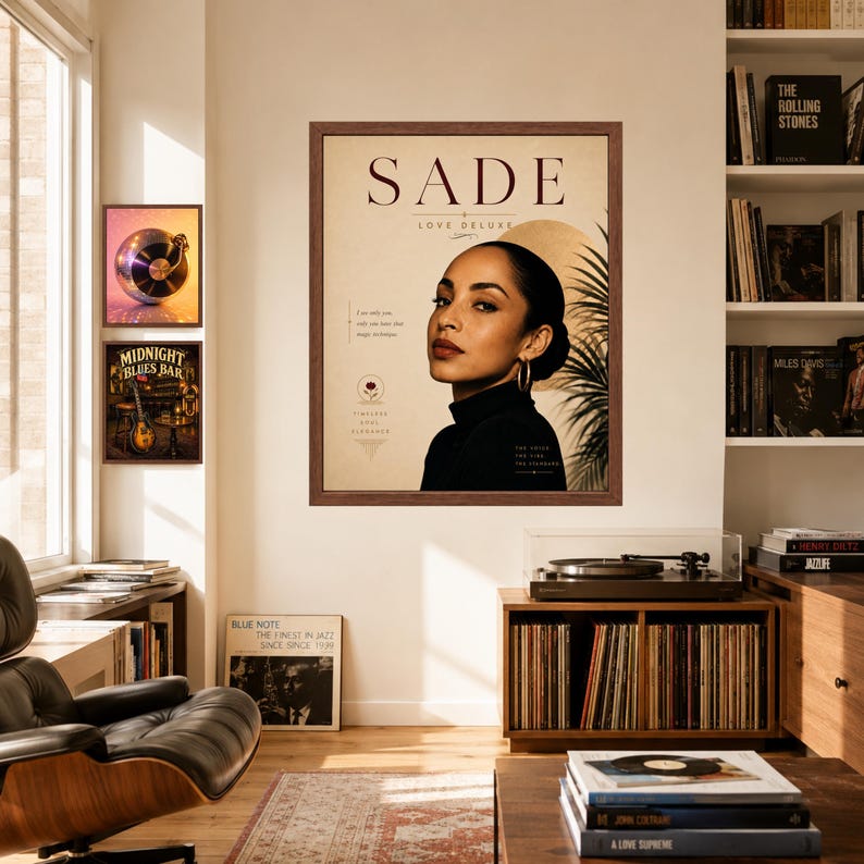 May include: A framed wall poster featuring a portrait of Sade with the text SADE LOVE DELUXE. The design includes a beige background, a golden circular element, and palm leaf silhouettes. The artist wears a black turtleneck and gold hoop earrings.