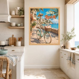 Peut inclure: Une impression d'art encadr&eacute;e repr&eacute;sentant un squelette portant un chapeau de paille et des lunettes de soleil, chevauchant un v&eacute;lo bleu clair sur un chemin c&ocirc;tier. Le texte BONE TO ROAM est &eacute;crit en lettres orange et bleues au-dessus.