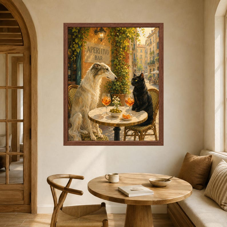 May include: A framed wall art print depicting a white Borzoi dog and a black cat sitting at a small round table outside an Aperitivo Bar. The table holds two orange cocktails and a small bowl of olives. The scene is set in a sunlit European street.