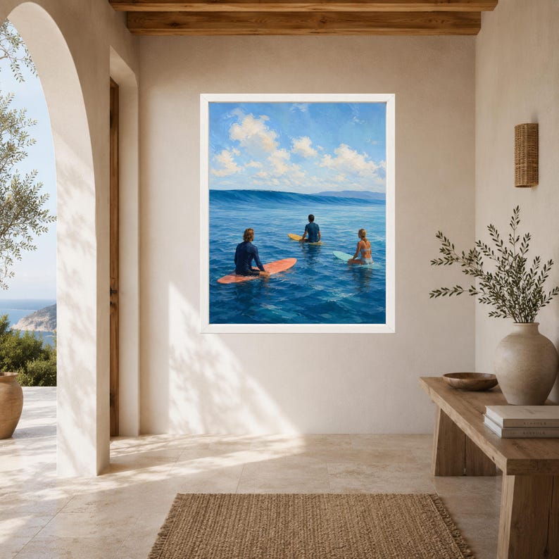 May include: A framed wall art print depicting three individuals on surfboards in the middle of a deep blue ocean under a bright sky with scattered white clouds. The surfers are positioned on orange, yellow, and light blue boards facing a wave.
