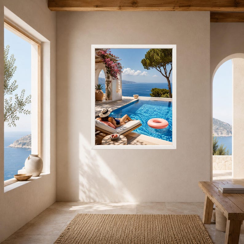 May include: A framed wall art print depicting a sunny coastal scene with a swimming pool, a person wearing a sun hat lounging on a deck chair, a pink inflatable ring floating in the water, and a view of the blue sea under a clear sky.