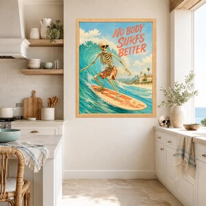 May include: A framed wall art print featuring a skeleton wearing sunglasses and patterned shorts while surfing on a large wave. The text NO BODY SURFS BETTER is printed in orange at the top right. The background shows a coastal scene with buildings.