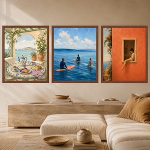 May include: A set of three framed wall art prints. The left print shows a table with a teapot and fruit overlooking the sea. The center print depicts three people on surfboards in the ocean. The right print shows a person sitting in a window.