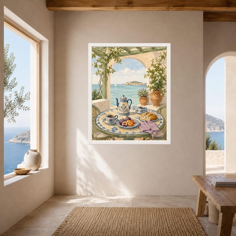 May include: A framed wall art print depicting a Mediterranean terrace scene with a round tiled table, a blue and white teapot, two cups, and a plate of fruit. The background shows a coastal view with a pergola, potted plants, and the sea.
