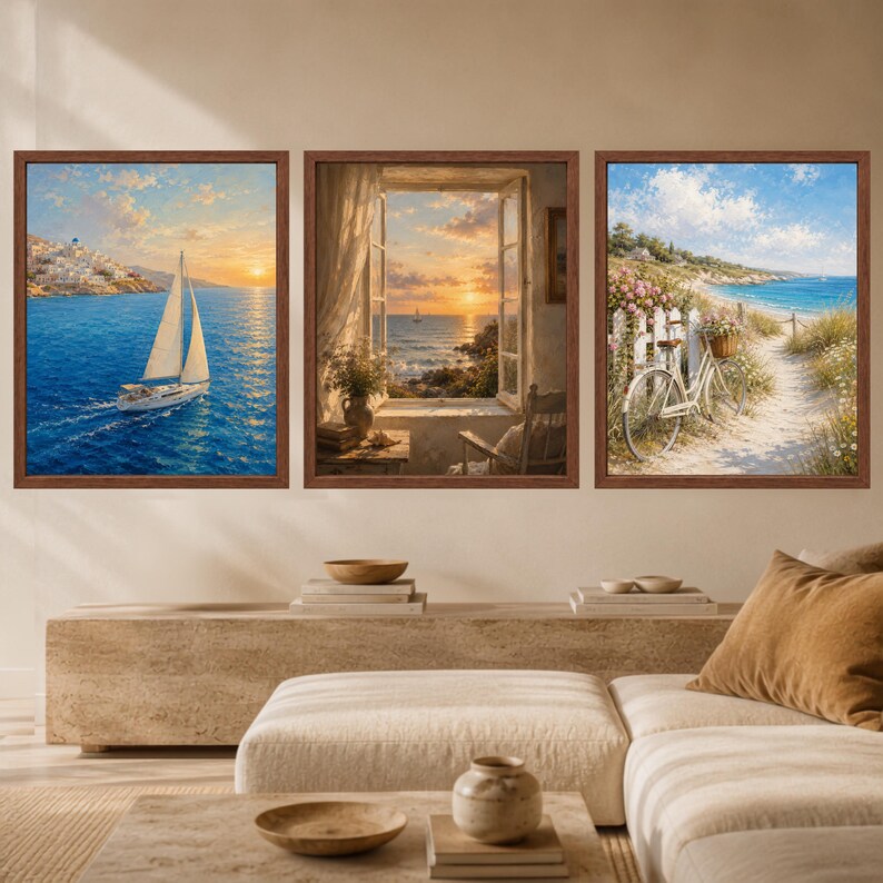 May include: A set of three framed wall art prints featuring coastal scenes. The left print shows a sailboat on blue water at sunset. The center print depicts an open window view of the ocean. The right print shows a bicycle on a sandy path.