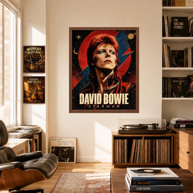May include: A framed wall poster featuring a portrait of David Bowie with red hair, blue eyeshadow, and a gold circular emblem on the forehead. The background displays a red circle and blue lightning bolt with the text DAVID BOWIE STARMAN.