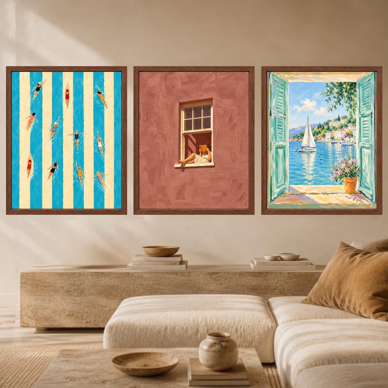 May include: Three framed wall art prints in dark wood frames. The left print shows swimmers in a blue and cream striped pool. The center print depicts a person reading in a window on a terracotta wall. The right print shows a coastal view.