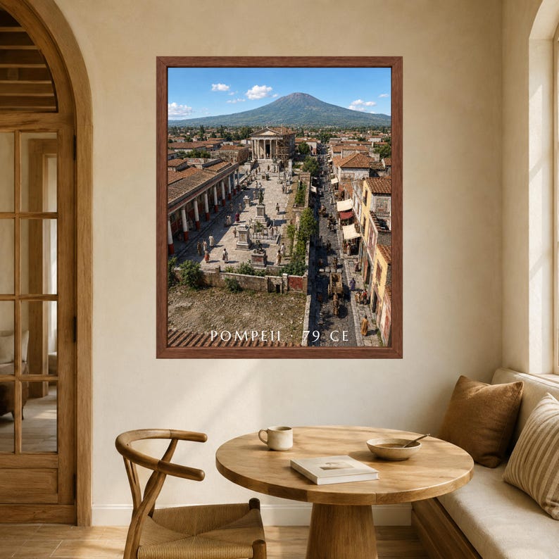 K&ouml;nnte beinhalten: Ein gerahmter Wandkunstdruck, der eine Luftaufnahme der antiken Stadt Pompeji mit dem Vesuv im Hintergrund zeigt. Das Bild zeigt Steingeb&auml;ude, einen zentralen Platz und den in Wei&szlig; am unteren Rand gedruckten Text POMPEII 79 CE.