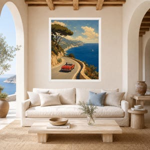 May include: A framed wall art print depicting a red convertible sports car driving along a winding coastal road overlooking a deep blue sea under a bright sky with scattered clouds, featuring a large tree on the cliffside and distant mountains.