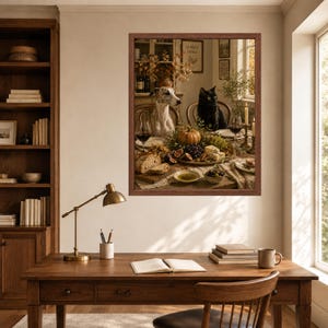 Op de afbeelding: Een ingelijste muurkunstprint met een grijs-witte hond en een zwarte kat aan een eettafel gedekt met een pompoen, druiven, vijgen, brood en wijnglazen. De sc&egrave;ne is vastgelegd in een warme, rustieke binnenomgeving met zachte verlichting.