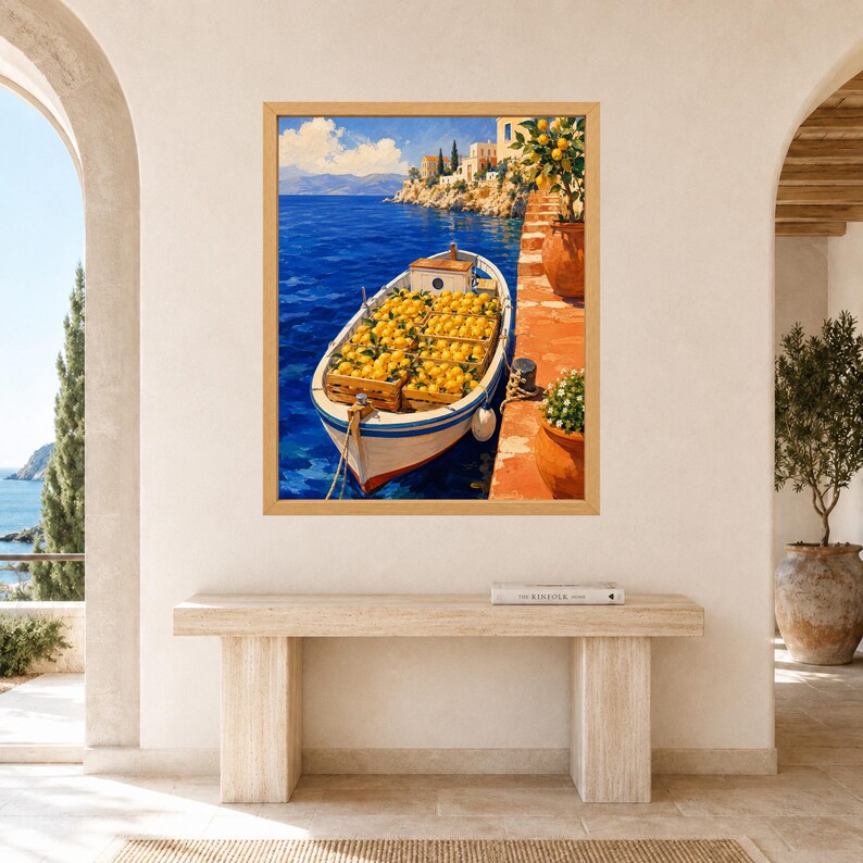 May include: A framed wall art print depicting a white boat filled with wooden crates of bright yellow lemons docked at a terracotta-colored pier. The scene features deep blue sea water, a distant rocky coastline with buildings, and a clear sky.