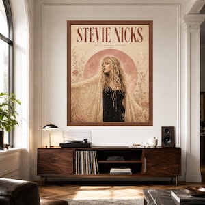 May include: A framed wall art print featuring a portrait of Stevie Nicks with the text "STEVIE NICKS" and "BELLA DONNA DREAMS" at the top. The image shows a person with long blonde hair wearing a black top and a lace shawl, set against a large pink moon.